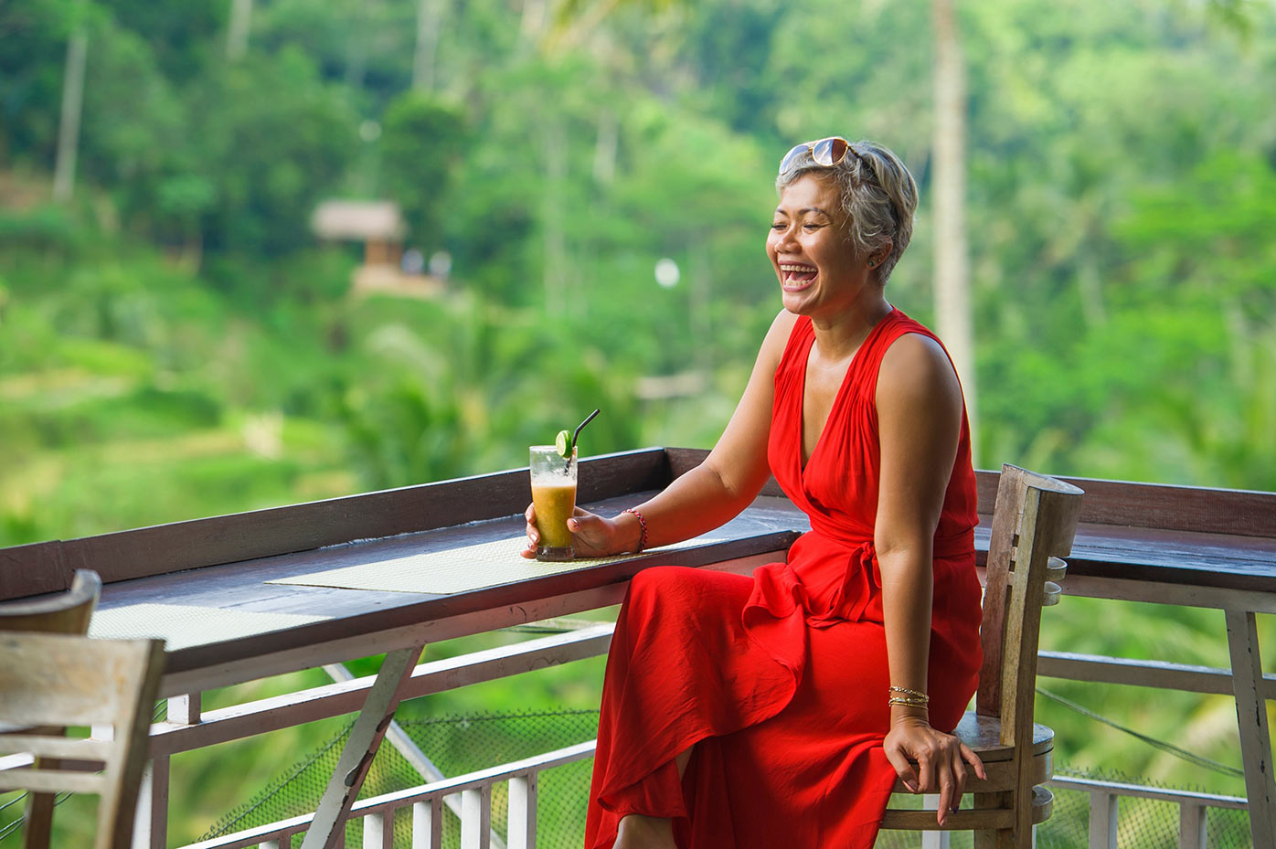 Asian woman sitting and laughing with a drink