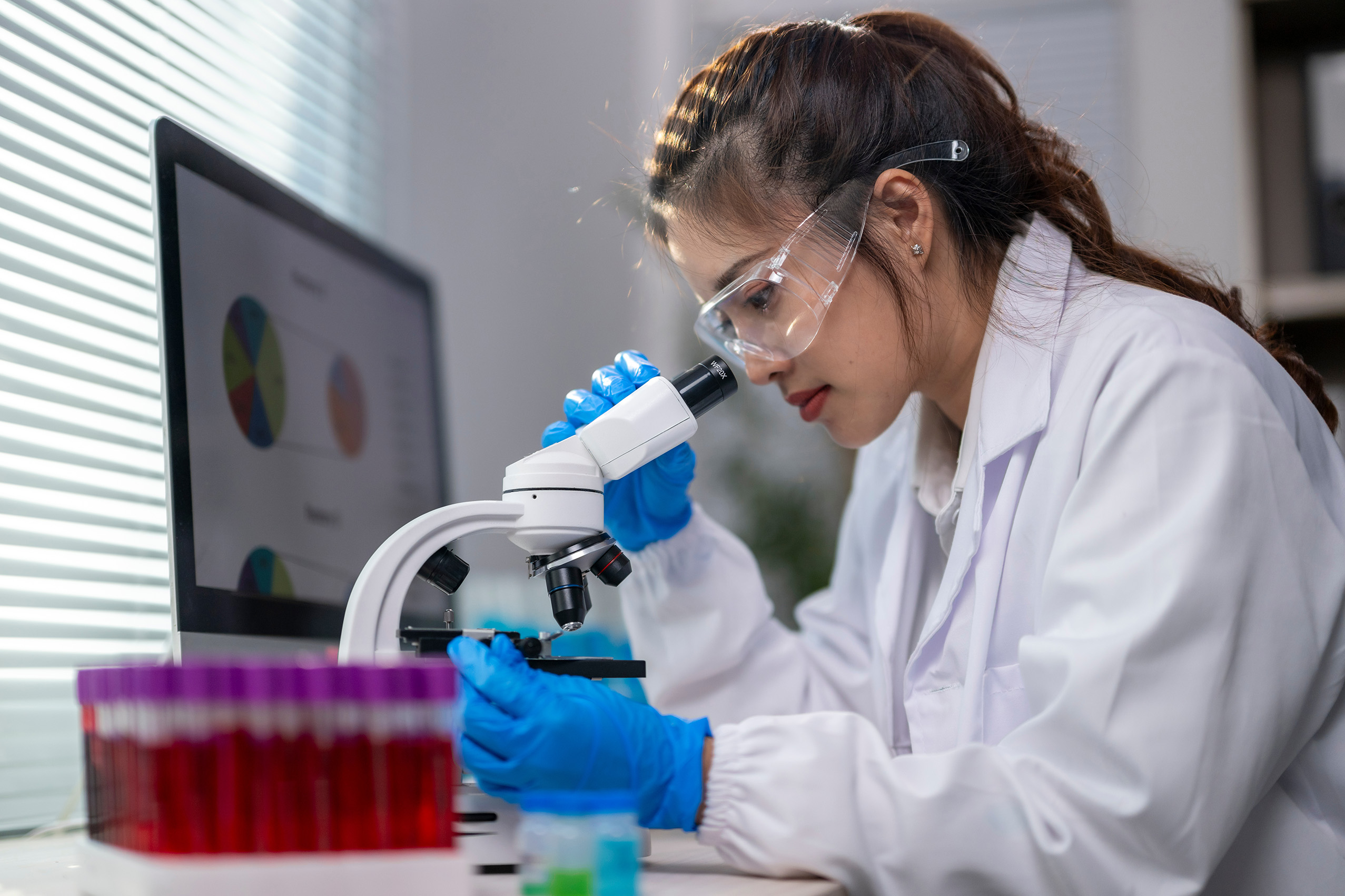 Woman looking in microscope in a lab.