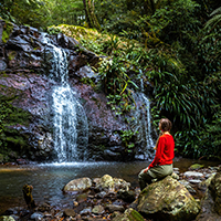 Woman sitting by a waterfall