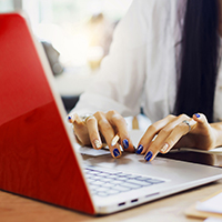 Woman typing on a red laptop
