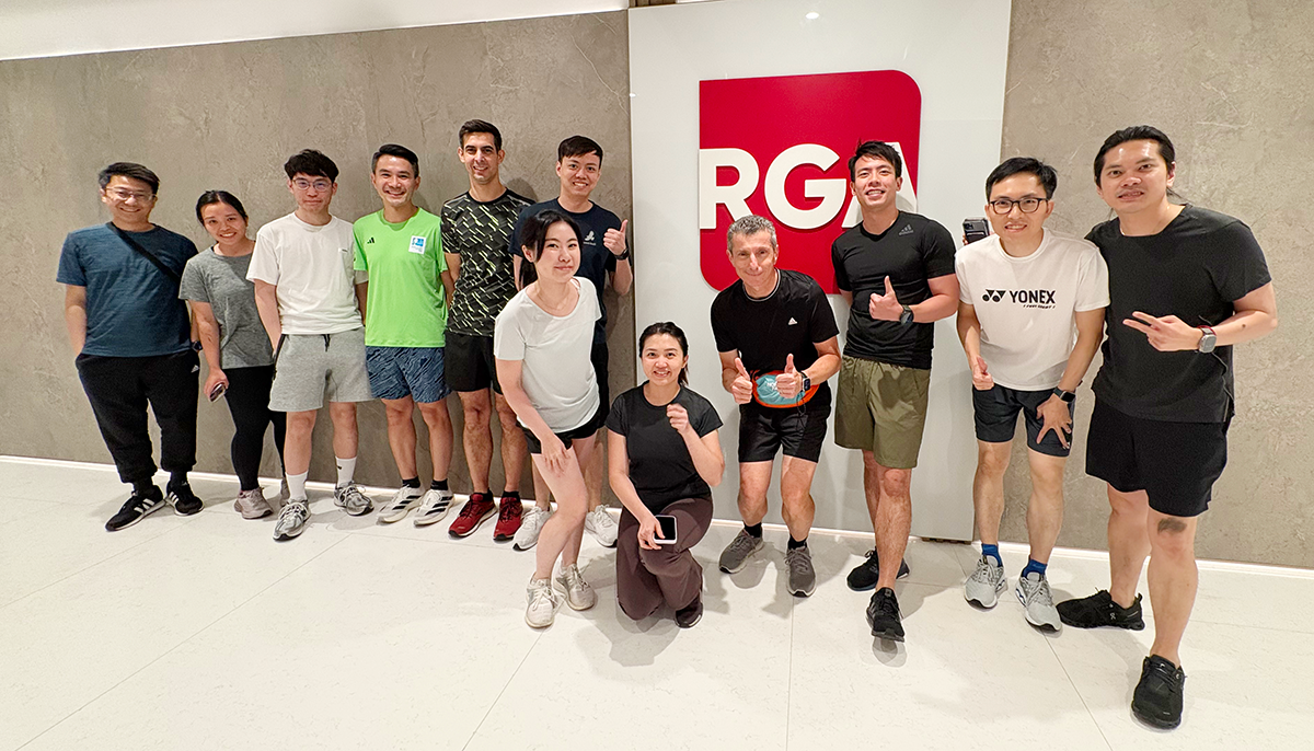 A group of RGA Hong Kong employees including Maurizio Busti gathers by the RGA logo before heading to a run.